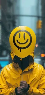 Person with yellow raincoat holding a smiley face balloon on a rainy city street.