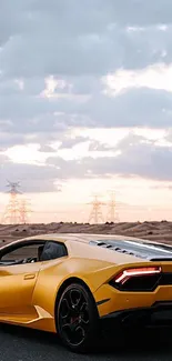 Sleek yellow sports car on a desert road under a cloudy sky.