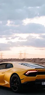 Yellow sports car driving on a desert road at sunset.