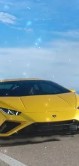 Yellow sports car on open road with blue sky background.