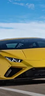 Yellow sports car driving on open road under blue sky.