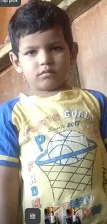 Child in yellow sports shirt in indoor setting.