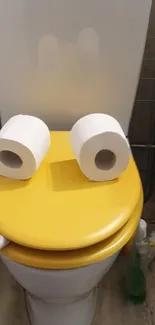 Yellow toilet seat with toilet paper eyes.