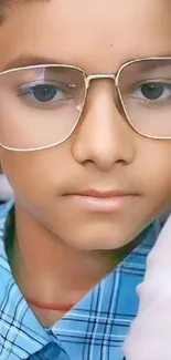 Young boy wearing glasses in blue shirt.