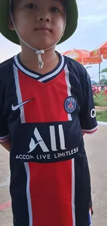 Young boy wearing a soccer jersey outdoors.