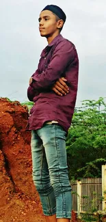 A young man stands outside, surrounded by a nature backdrop.