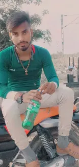 Young man sitting on motorcycle, wearing green shirt.