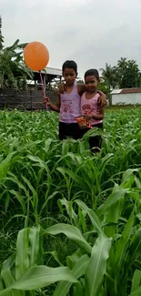 Children in lush green field holding a balloon on a cloudy day.