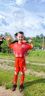 Young soccer player in red uniform on a green field under a blue sky.