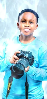 Young photographer in blue holding camera against a blue background.