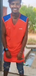 Young man smiling in a bright red sports outfit outdoors.