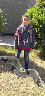 Boy in garden with seagull and pink petals on a spring day.