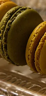 Close-up of colorful green and golden macarons on a glass plate.