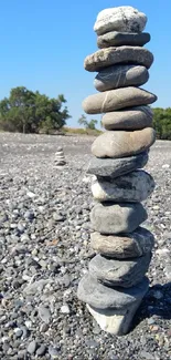 Stack of zen stones on a sunny beach with blue sky backdrop.